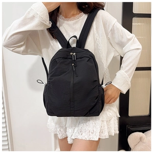 Detail of minimalist black nylon backpack featuring adjustable drawstring side pockets