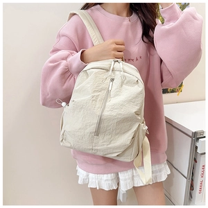 Detail of minimalist cream nylon backpack featuring a textured finish and vertical zipper