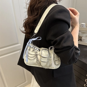 Minimalist cream shoulder bag with punk chains and star rivets worn by model in black suit