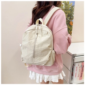 Rear view of model wearing a minimalist beige nylon backpack with multi-zipper pockets