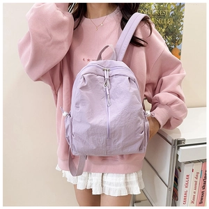 Detail view of a light purple nylon backpack featuring a vertical zipper and side buckle straps