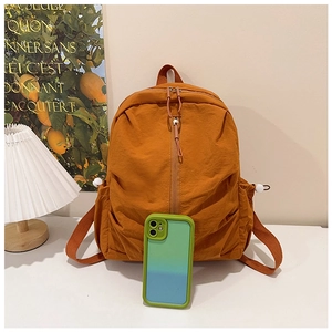 Detail of a bright orange nylon backpack featuring side drawstring pockets and a sleek design