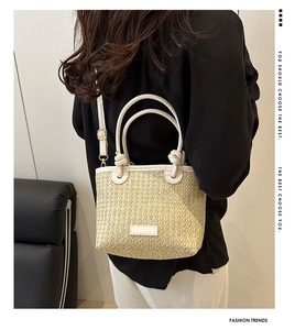 Detail of straw woven bucket bag with cream leather knot handles and a detachable strap