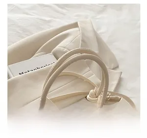 Detail of comfortable knot handle and metal hooks on a beige woven straw basket bag
