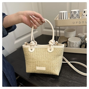 Detail of straw bucket bag with white leather trim and detachable shoulder strap