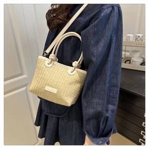 Detail of woven straw bucket bag with cream handles and adjustable shoulder strap