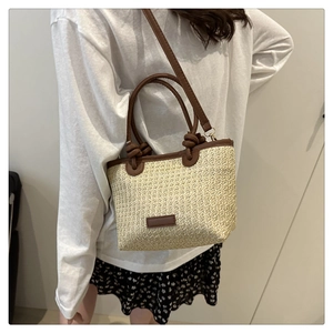 Detail of straw bucket bag with brown leather trim and detachable shoulder strap