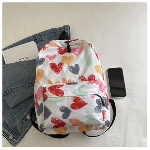 Détail des motifs cœurs graffiti colorés sur un sac à dos blanc léger avec poche avant