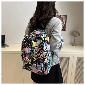 Student backpack with colorful graffiti print shown on a model in a cozy indoor setting