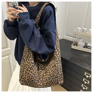 Detail of large leopard print canvas tote bag with wide shoulder strap shown on model