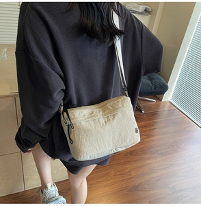 Model wearing a minimalist beige nylon crossbody messenger bag with adjustable strap