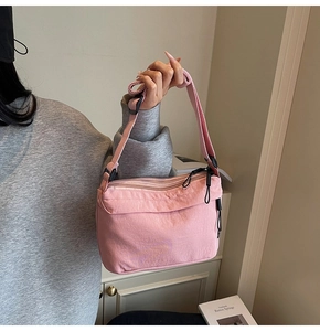 Pink nylon crossbody bag with three zipper compartments and wide adjustable shoulder strap