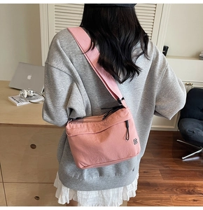 Pink nylon crossbody bag detail with clover logo and adjustable wide shoulder strap