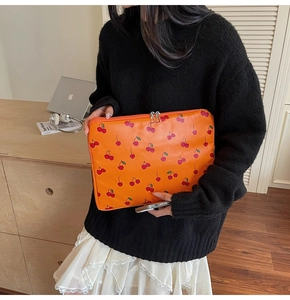 Detailed close-up of orange cherry print laptop sleeve with dual metal zippers