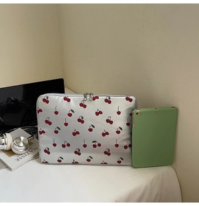 Close-up of silver laptop sleeve with cherry pattern and dual metal zippers