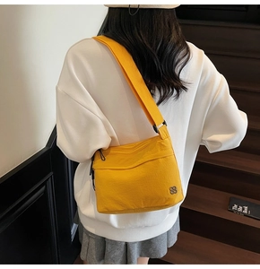 Rear view of model wearing bright yellow canvas crossbody bag on wooden stairs