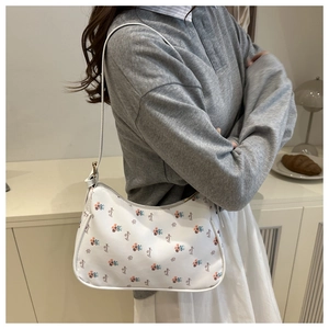Detail of floral canvas hobo bag with zip closure and elegant shoulder strap on model