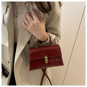 Close-up of retro burgundy patent leather handbag featuring a golden capsule metal clasp