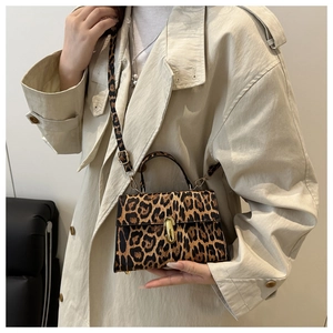 Détail du sac bandoulière léopard avec boucle dorée et texture sur un trench-coat élégant