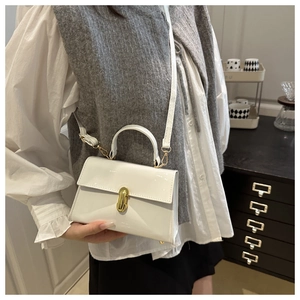 Détail du sac à bandoulière en cuir verni blanc avec fermoir tournant en métal doré