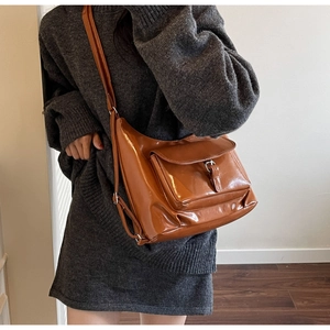 Close-up of caramel brown patent leather shoulder bag with metallic buckle detail
