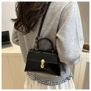 Détail du sac à main en cuir verni noir avec fermoir colonne doré et bandoulière réglable