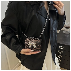 Detail of leopard print crossbody bag with silver bow buckle and metal chain strap