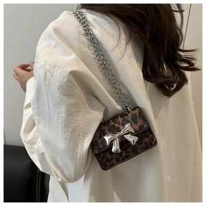 Detail of leopard print crossbody bag with metallic silver bow clasp and chain strap