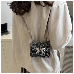 Macro detail of leopard print crossbody bag featuring silver metallic bow clasp and chain