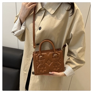 Detail of vintage brown shoulder bag with floral embossing and gold hardware