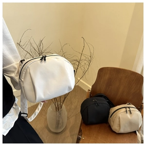 Three minimalist nylon crescent bags in white black and beige colors with wide straps