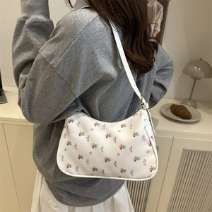 Vintage white hobo shoulder bag with floral print worn by a model in a cozy room