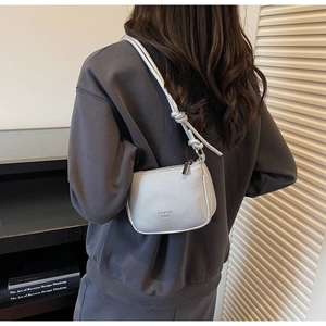 Detail of silver litchi texture shoulder bag with knot strap and brand logo