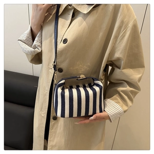 Detail of blue and white striped tote bag with gold snap closure and leather strap