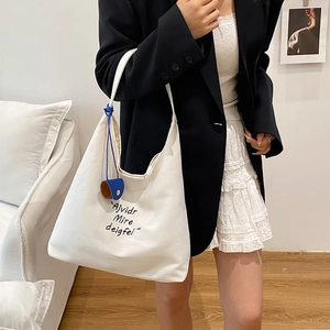 Large white canvas tote bag with black lettering and blue pouch for daily commuting