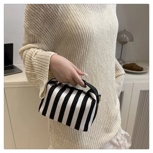 Detail of black and white striped canvas tote with leather handle and gold hardware