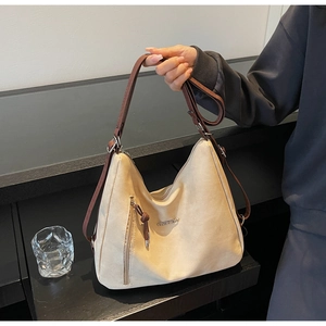 Detail view of large hobo bag with apricot suede finish and fashion metal logo