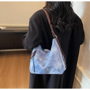 Detail of blue textured hobo bag with FASHION metal logo and brown leather strap