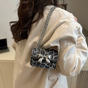 Chic leopard print crossbody bag with silver bow accent on beige trench coat model