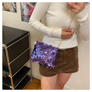 Detail of purple sequin crossbody bag with gold chain strap in a fashion lifestyle setting