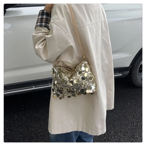 Detailed view of fashionable gold sequin chain bag worn outdoors by a model