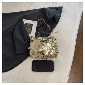 Detail of a mini gold sequin handbag with chain strap shown with a phone for size scale