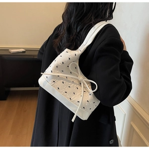 Détail d'un sac à bandoulière blanc avec nœud décoratif et motif imprimé lapin