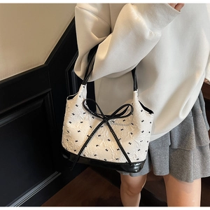 Détail du sac bandoulière tendance à motif nœuds avec garniture en cuir contrastée