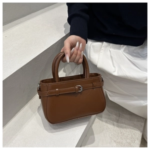 Detalle de un bolso de mano marrón mate con hebilla metálica elegante y dos asas redondas