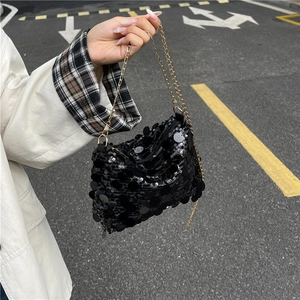 Fashionable black sequin crossbody bag with gold chain strap shown in a street style shot