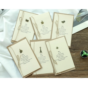 Detail of vintage handmade greeting cards with bronze charms and twine on kraft paper