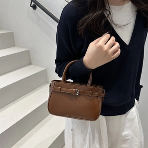 Sac à main chic en cuir synthétique marron avec boucle argentée sur un escalier en pierre