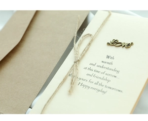 Detail of vintage greeting card with kraft envelope, rustic twine, and metal Love charm