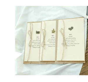 Detail of vintage kraft paper cards with metal charms and twine on white fabric